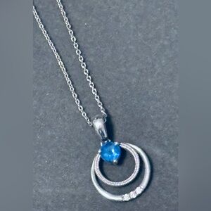 Sapphire stone with tiny diamonds set in a sterling silver necklace.